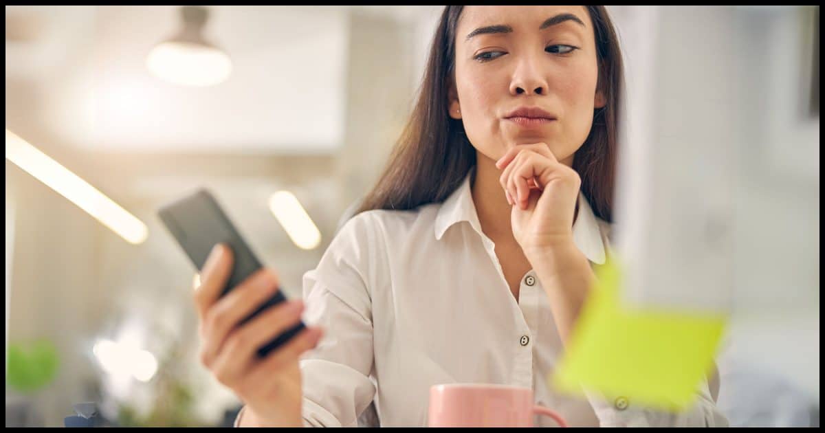 A woman looking at her mobile phone with suspicion.